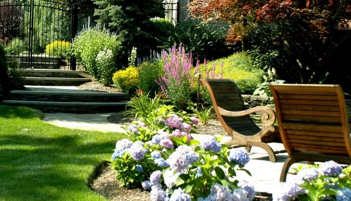 beautiful landscape with green grass, flowers and outdoor seating