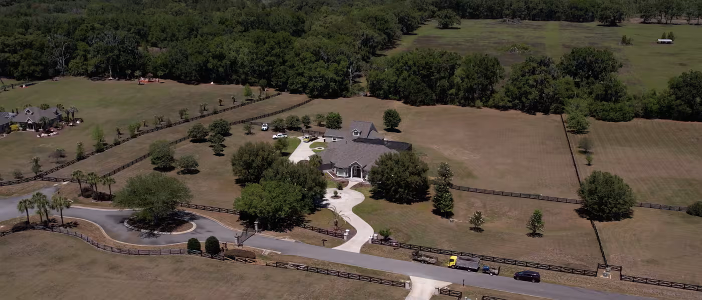 Aerial view of the property showcasing the expansive landscape, surrounding acreage, and completed outdoor improvements.