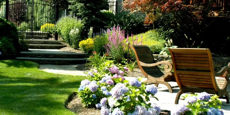 beautiful landscape with green grass, flowers and outdoor seating