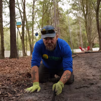 Landscape crew member shaping the edge of a custom pathway during backyard landscape construction.