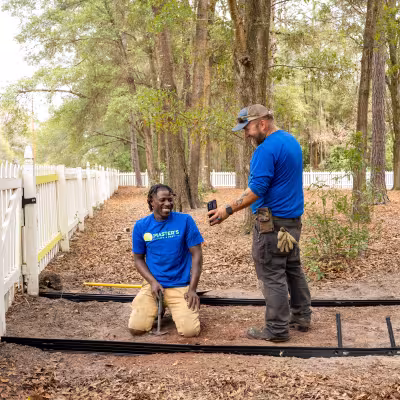 Landscape crew members smiling and reviewing progress during a custom pathway installation project.