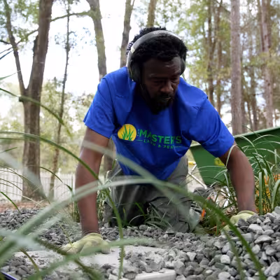 Landscape team member placing decorative stone around a newly installed backyard pathway.
