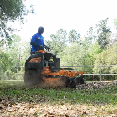 Landscape technician operating a mower while maintaining common areas at Southern Grove Condominiums.