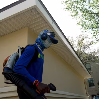 Landscape technician using a backpack blower to maintain condominium grounds and building exteriors.