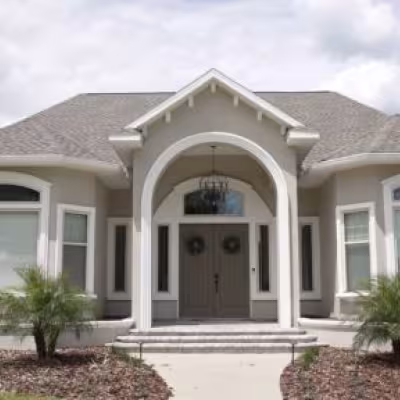 Front entrance after landscape renovation featuring symmetrical palm plantings and refreshed landscape beds.
