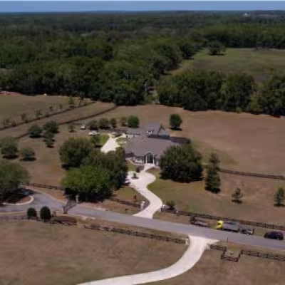 Aerial view of the Gainesville property showing the home, driveway, lawn, surrounding acreage, and landscape.