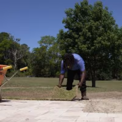 Landscape team member preparing soil beside the driveway during new sod installation.