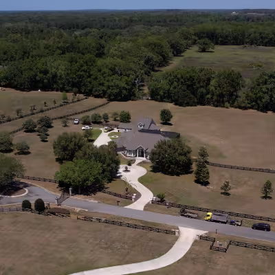 Aerial view of the property showcasing the expansive landscape, surrounding acreage, and completed outdoor improvements.