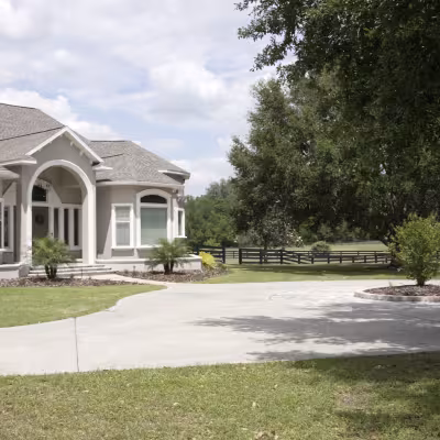 Wide view of the front of the home showcasing the refreshed landscaping and circular driveway.