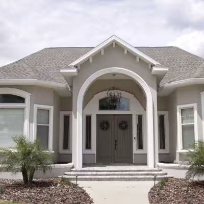 Front view of the home showcasing the refreshed landscape beds, palms, plantings, and updated entrance.