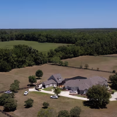 Aerial view of the home and surrounding acreage highlighting the scale of the property and landscape project.